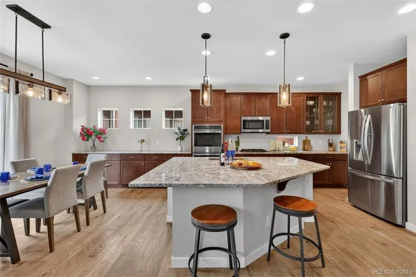 a kitchen with stainless steel appliances granite countertop a stove refrigerator and wooden floor