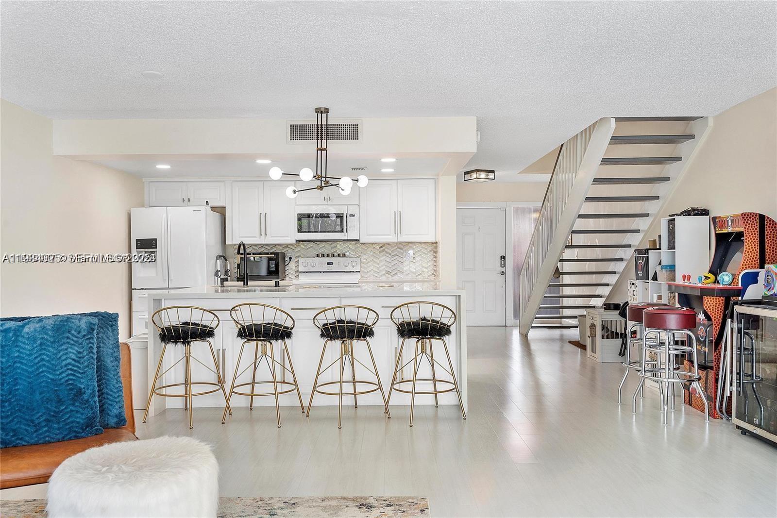 1281 West Fairway Road Pembroke Pines, FL 33026 - Photo 11 of 29 a kitchen with stainless steel appliances kitchen island granite countertop a table chairs and a living room