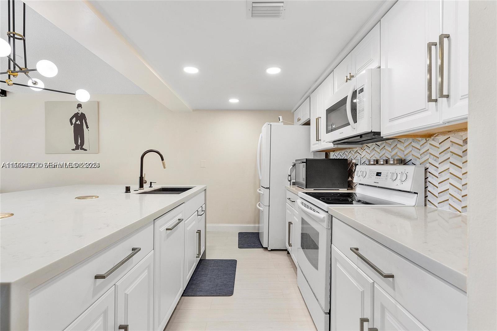 1281 West Fairway Road Pembroke Pines, FL 33026 - Photo 9 of 29 a kitchen with white cabinets and white appliances