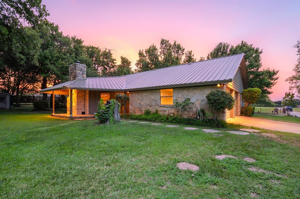 515 New Highland Road Springtown, TX 76082 - Photo 38 of 38 Stone facade home featuring a metal roof, covered front porch, and an attached garage