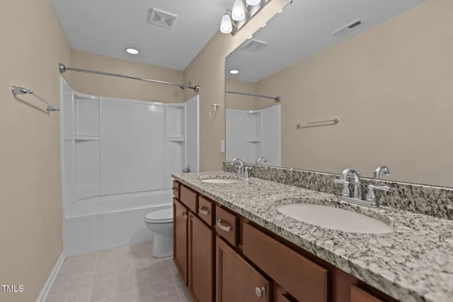 a bathroom with a granite countertop sink a toilet and shower