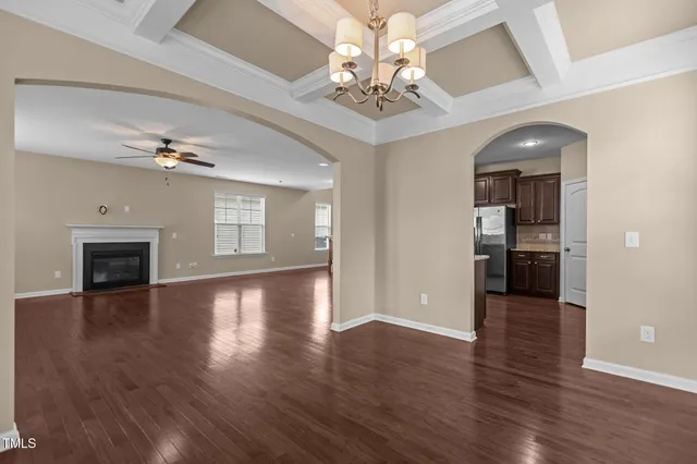 an empty room with wooden floor chandelier and livingroom