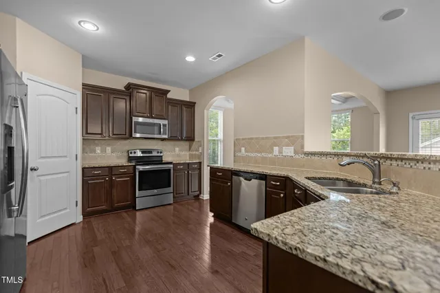 a kitchen with stainless steel appliances granite countertop a sink stove and refrigerator