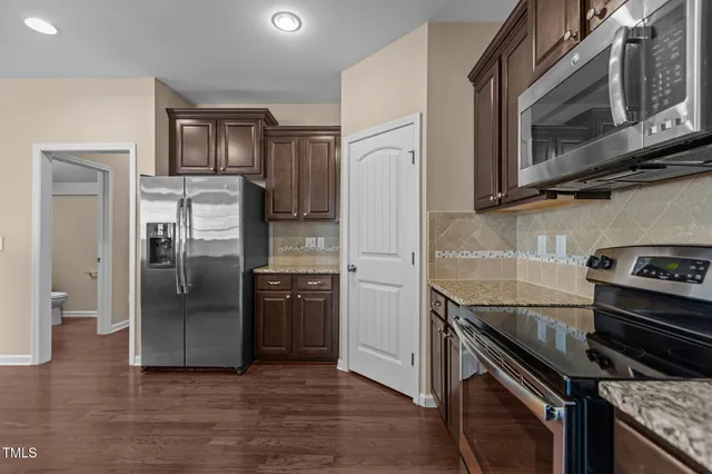 a kitchen with stainless steel appliances granite countertop a refrigerator and a stove top oven