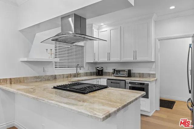 a kitchen with a stove a sink and white cabinets
