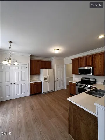 a kitchen with stainless steel appliances a stove top oven a sink dishwasher and a microwave oven on the wooden floor