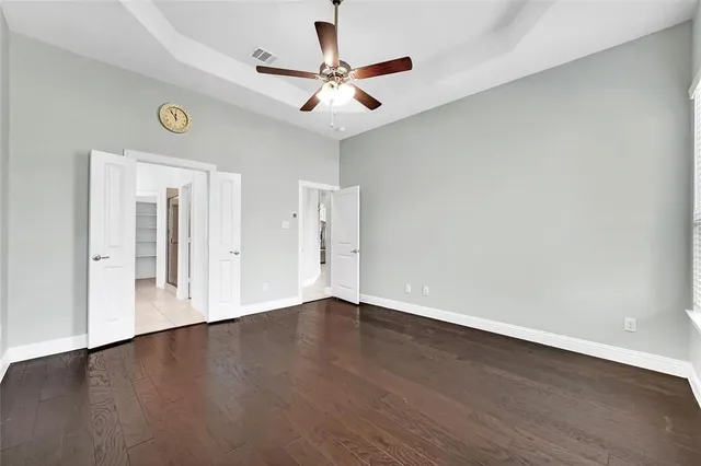an empty room with wooden floor and a ceiling fan