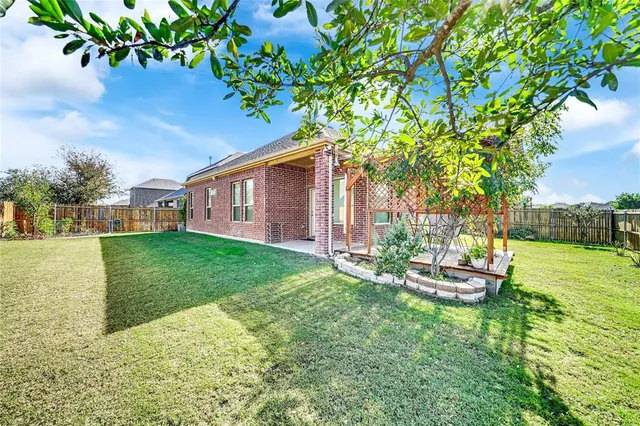 a backyard of a house with table and chairs plants and large tree