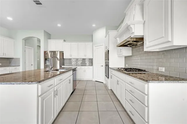 a large kitchen with stainless steel appliances granite countertop a stove a sink and a granite counter tops