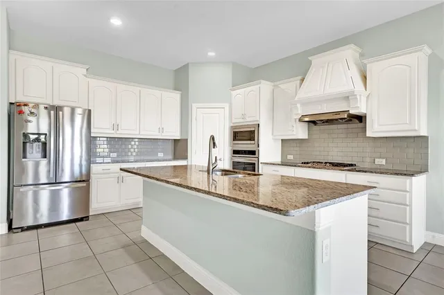 a kitchen with stainless steel appliances granite countertop a sink a stove a refrigerator and cabinets