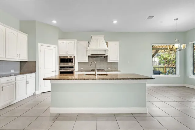a large kitchen with kitchen island granite countertop a stove a sink and a granite counter tops