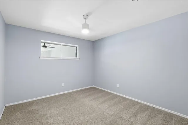 an empty room with a ceiling fan and window