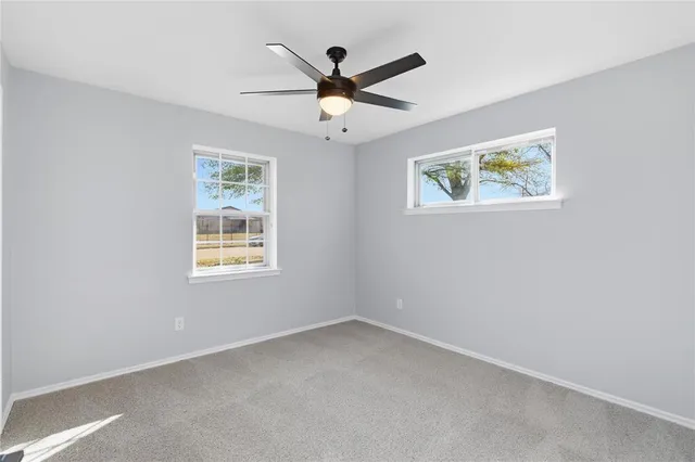 an empty room with window and ceiling fan