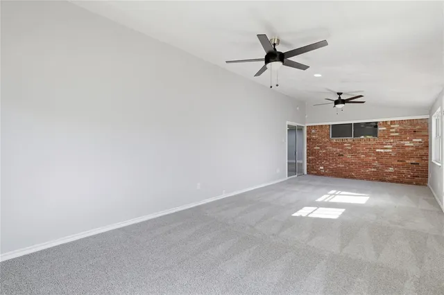 an empty room with ceiling fan and window
