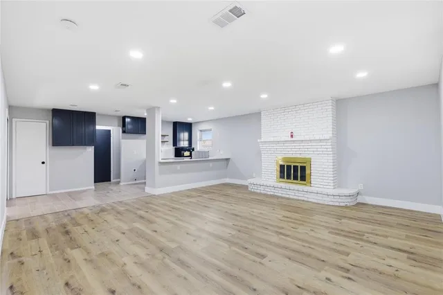 a view of an empty room with a kitchen and a window