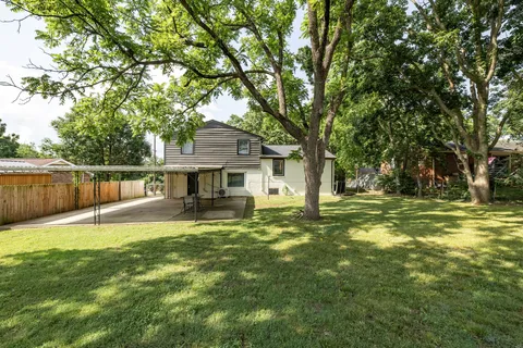 a view of a house with a large tree and a yard