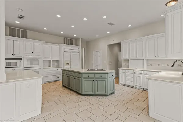 a large kitchen with stainless steel appliances granite countertop a large kitchen island white cabinets and sink