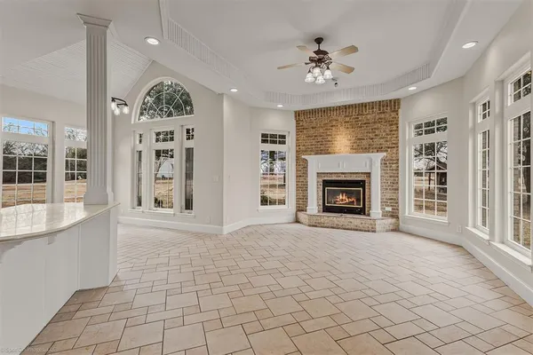 an empty room with windows fireplace and a kitchen view
