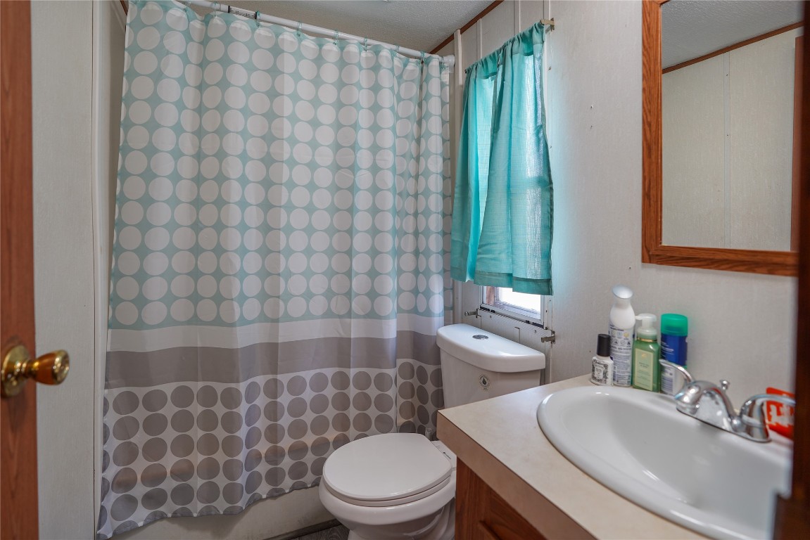 207 Riverside Street Highlands, TX 77562 - Photo 27 of 29 a bathroom with a sink a toilet and shower curtain
