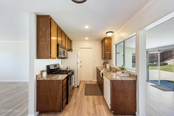 a kitchen with stainless steel appliances a stove top oven a sink a refrigerator and wooden floor