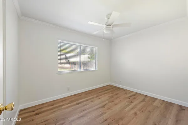 an empty room with wooden floor and chandelier fan