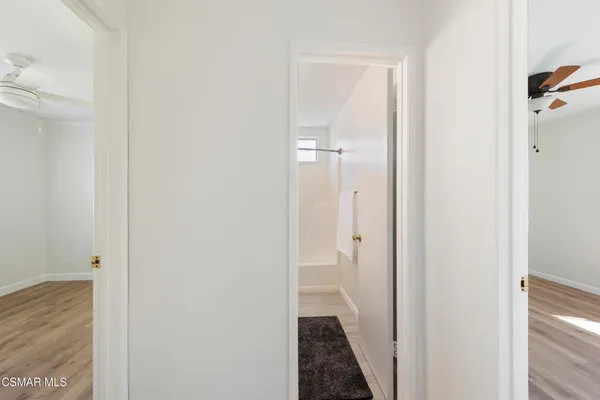 a view of empty room with wooden floor and fan