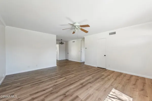 an empty room with wooden floor and ceiling fan