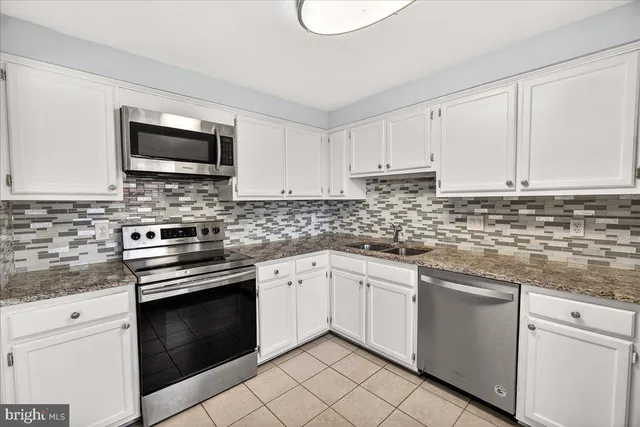 a kitchen with white cabinets appliances and a sink