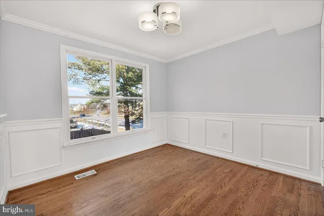 an empty room with wooden floor cabinet and windows