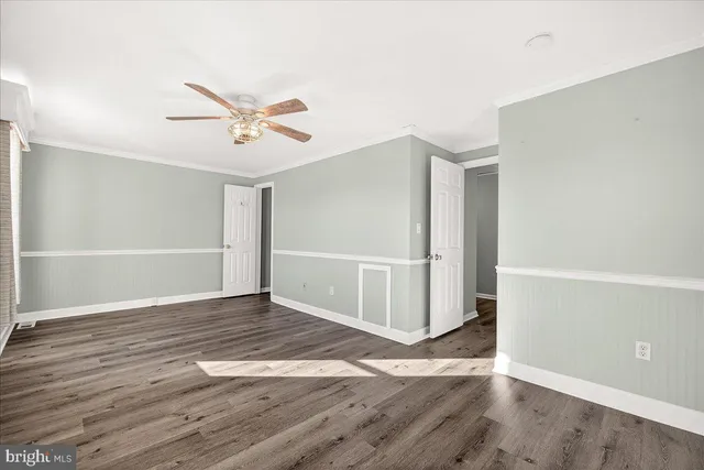 an empty room with wooden floor and ceiling fan