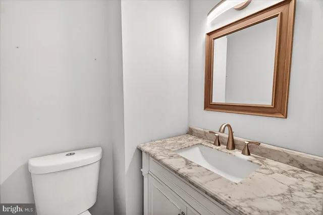a bathroom with a granite countertop toilet sink and mirror