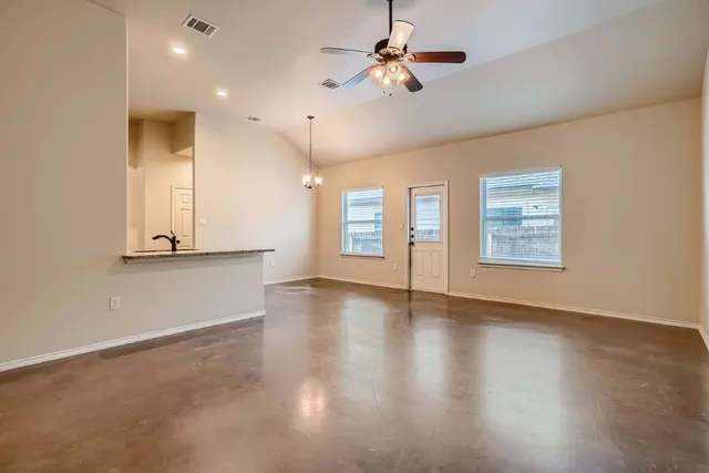 a view of an empty room with window and wooden floor