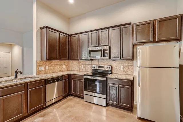 a kitchen with stainless steel appliances granite countertop a refrigerator sink and stove