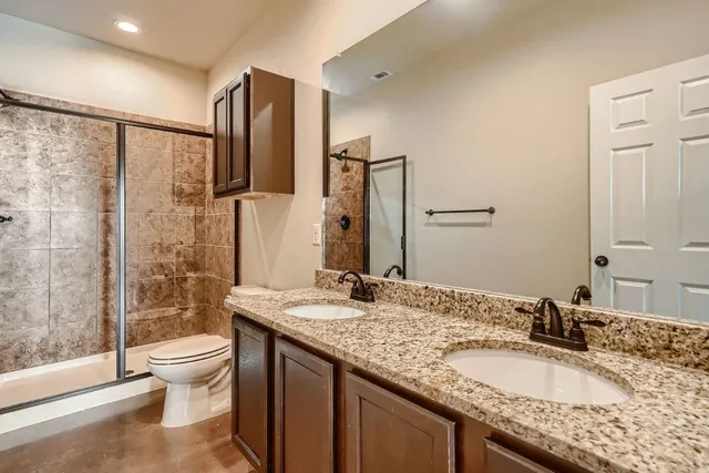a bathroom with a granite countertop sink toilet and shower