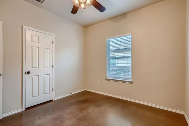 an empty room with a window and ceiling fan