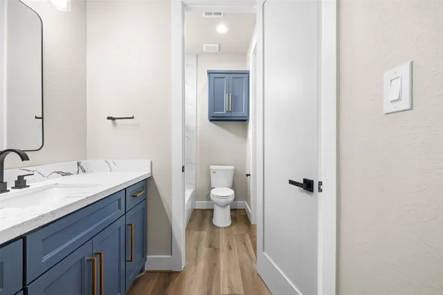 a bathroom with a granite countertop toilet a sink and a mirror
