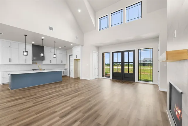 a large white kitchen with wooden floors and a large window