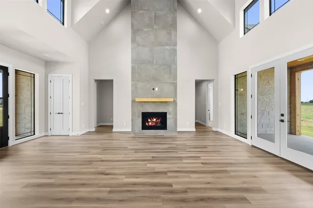 a view of an empty room with wooden floor fireplace and a window