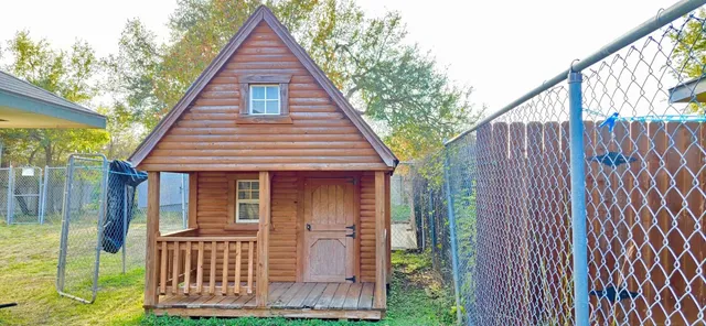 a view of a house with wooden fence next to a yard