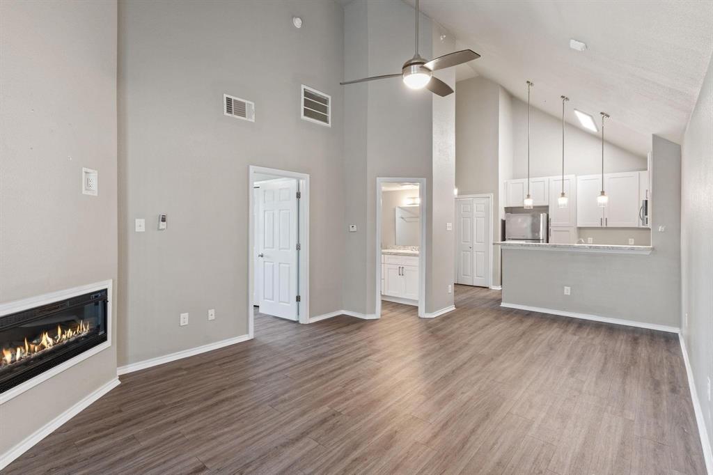 6108 Abrams Road, Unit 521 Dallas, TX 75231 - Photo 16 of 20 Open concept living area featuring wood-finish flooring, a linear fireplace, and vaulted ceilings