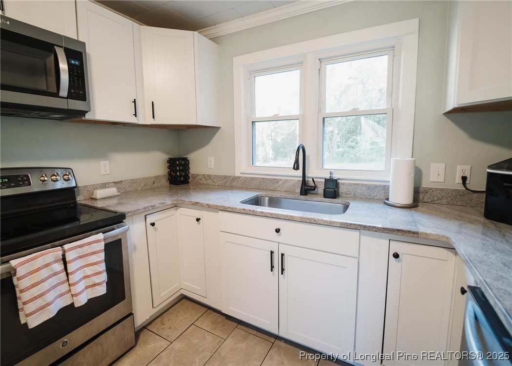 9778 Highway 24 Carthage, NC 28327 - Photo 12 of 47 a kitchen with granite countertop white cabinets stainless steel appliances a sink and a window