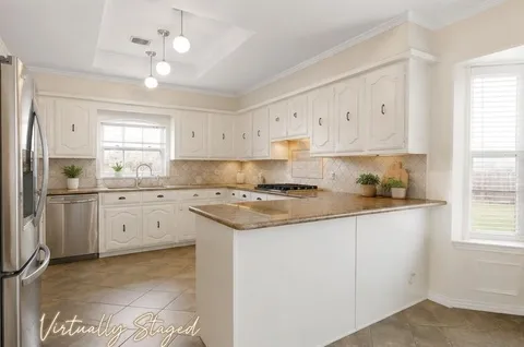 a kitchen with granite countertop a sink cabinets stainless steel appliances and a window