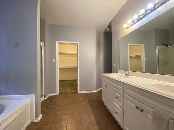 a bathroom with a double vanity sink a large mirror and a bathtub