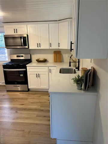 a kitchen with stainless steel appliances a stove a sink and white cabinets