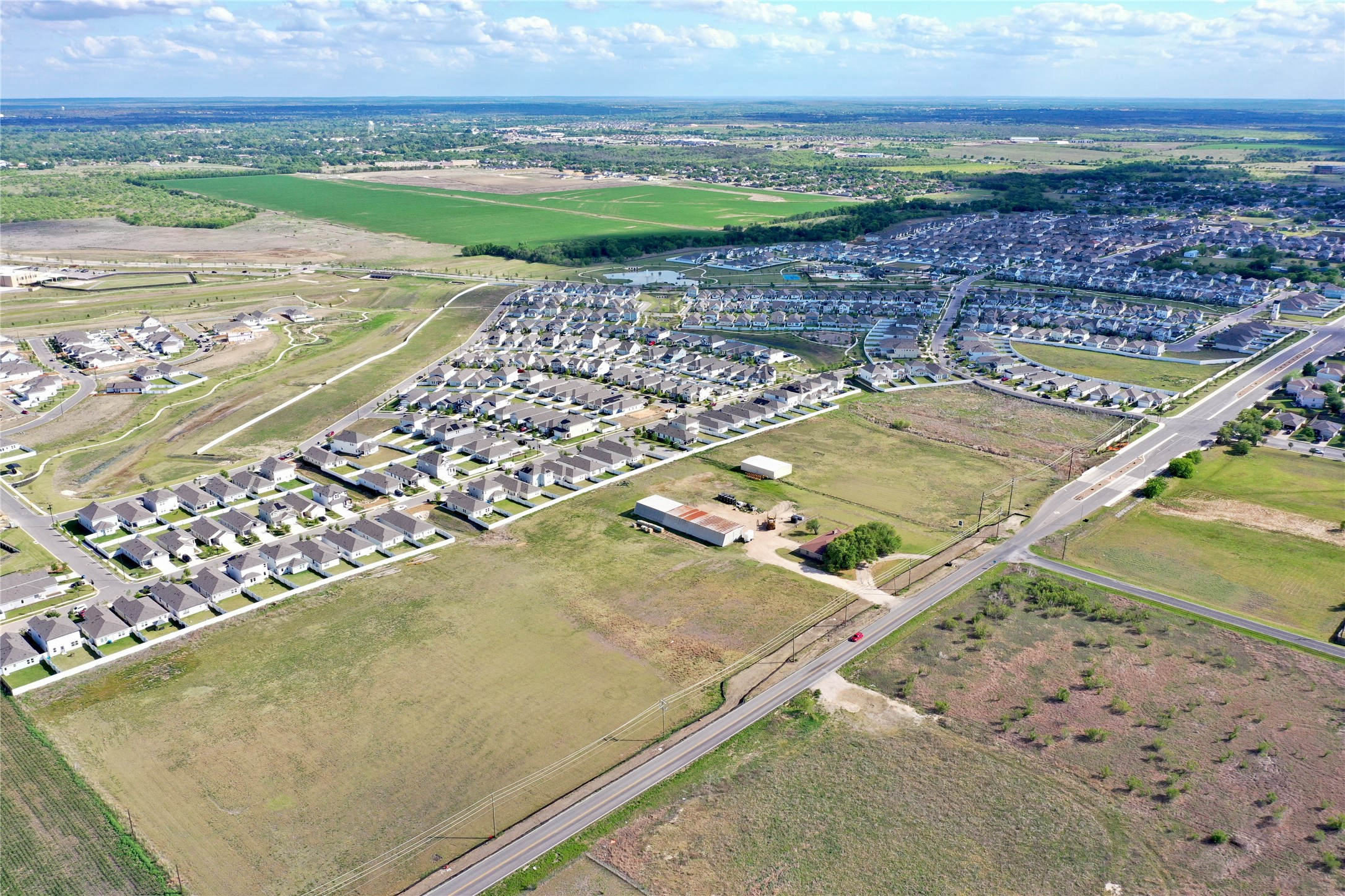 14601 County Line Road Elgin, TX 78621 - Photo 4 of 5 An aerial panorama reveals a vast residential community nestled alongside expansive green fields.