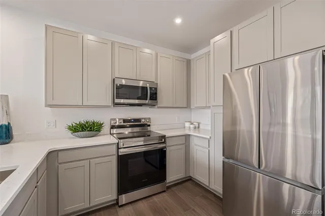 a kitchen with white cabinets stainless steel appliances and wooden floor