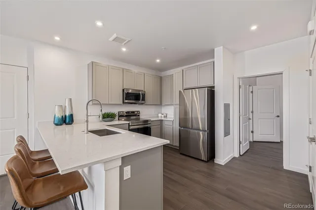 a kitchen with a refrigerator a stove top oven a sink and dishwasher with wooden floor