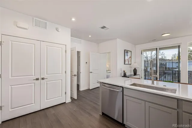 a hall with kitchen island white cabinets and wooden floor