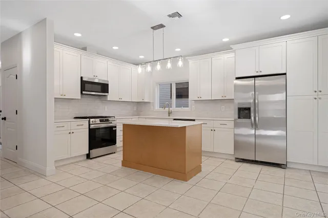 a kitchen with kitchen island a counter top space cabinets and stainless steel appliances