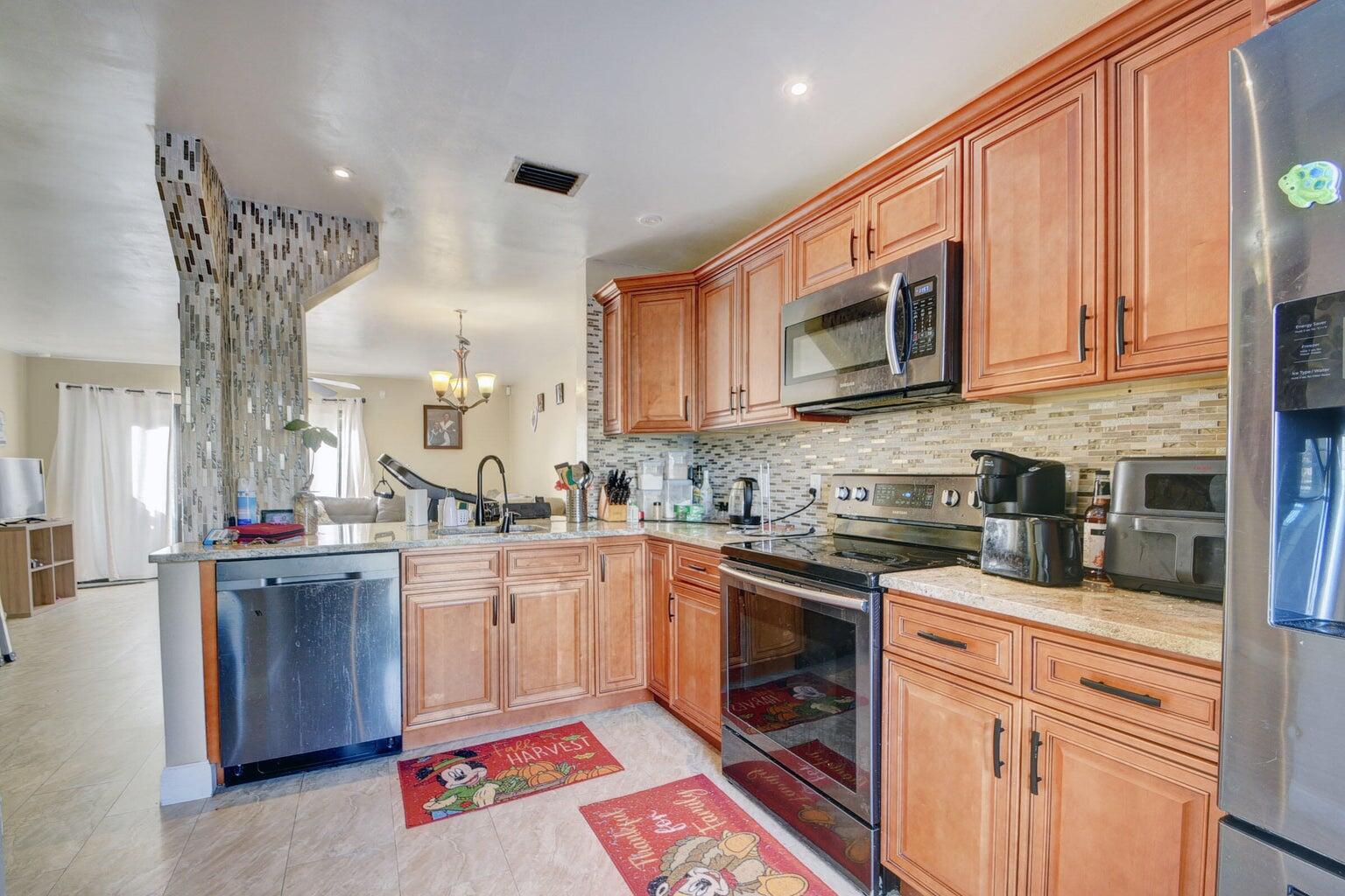 799 Hill Drive, Unit F West Palm Beach, FL 33415 - Photo 2 of 14 a kitchen with stainless steel appliances granite countertop a stove sink and cabinets